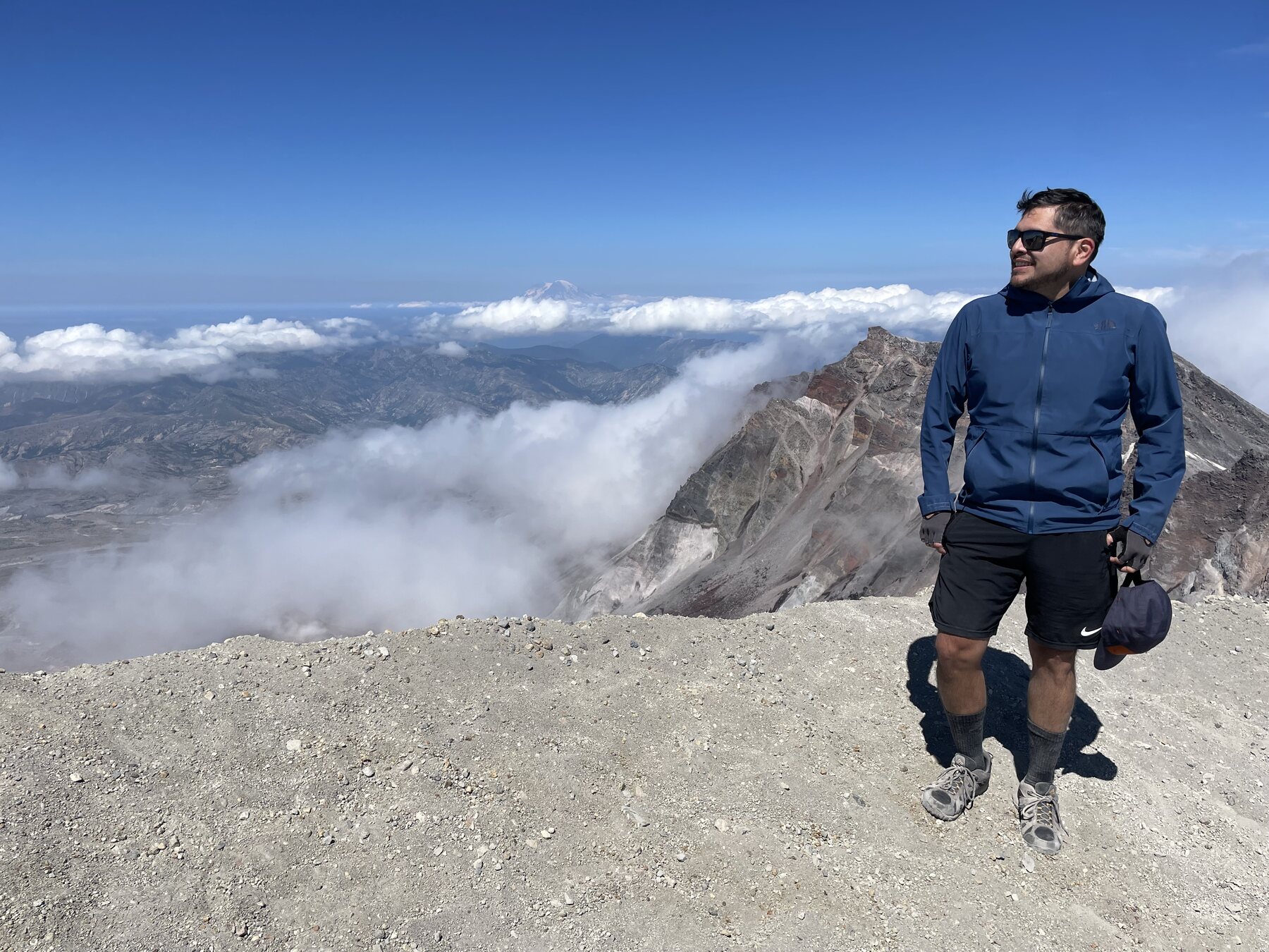 Antonio Olivas-Martinez at the summit of Mount St. Helens, with the crater and distant mountains behind him